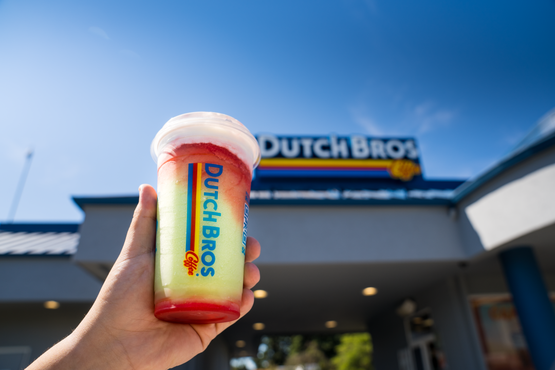 Person holding a drink in front of Dutch Bros Coffee Shop