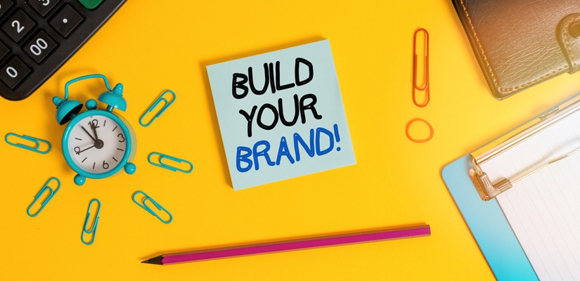 A yellow sticky note with the words "Build your brand!" written in black marker