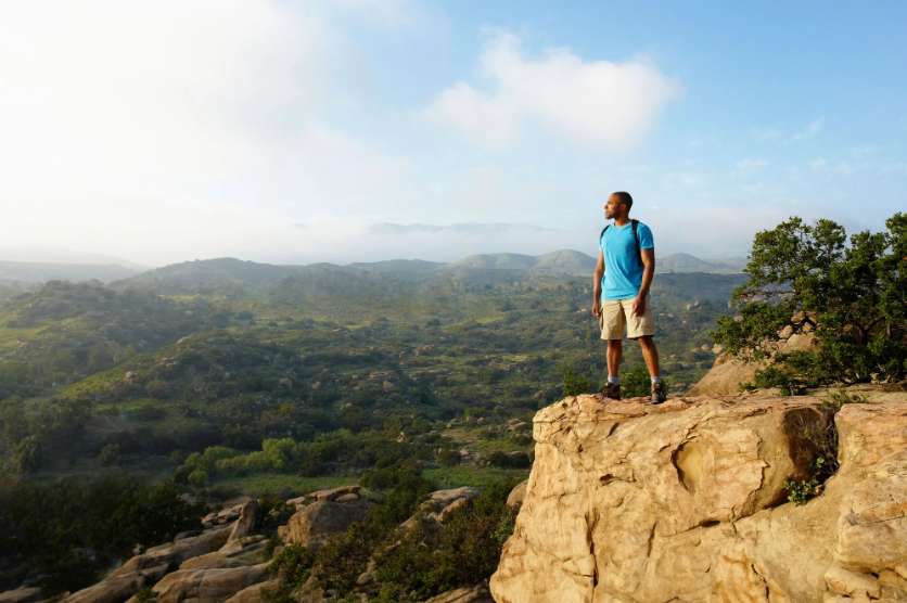 A male hiker looking out over a valley at sunset.